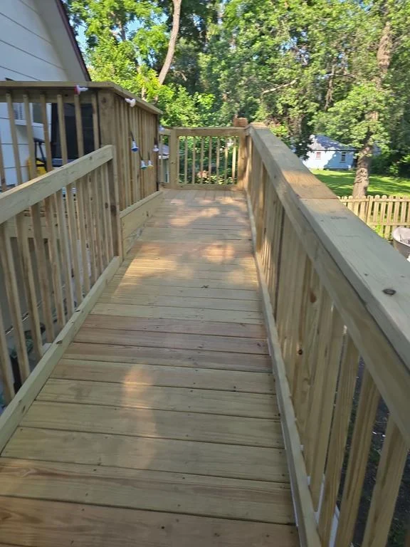 Close view along the wooden ramp walkway, showing the deck boards, handrails and vertical railing balusters